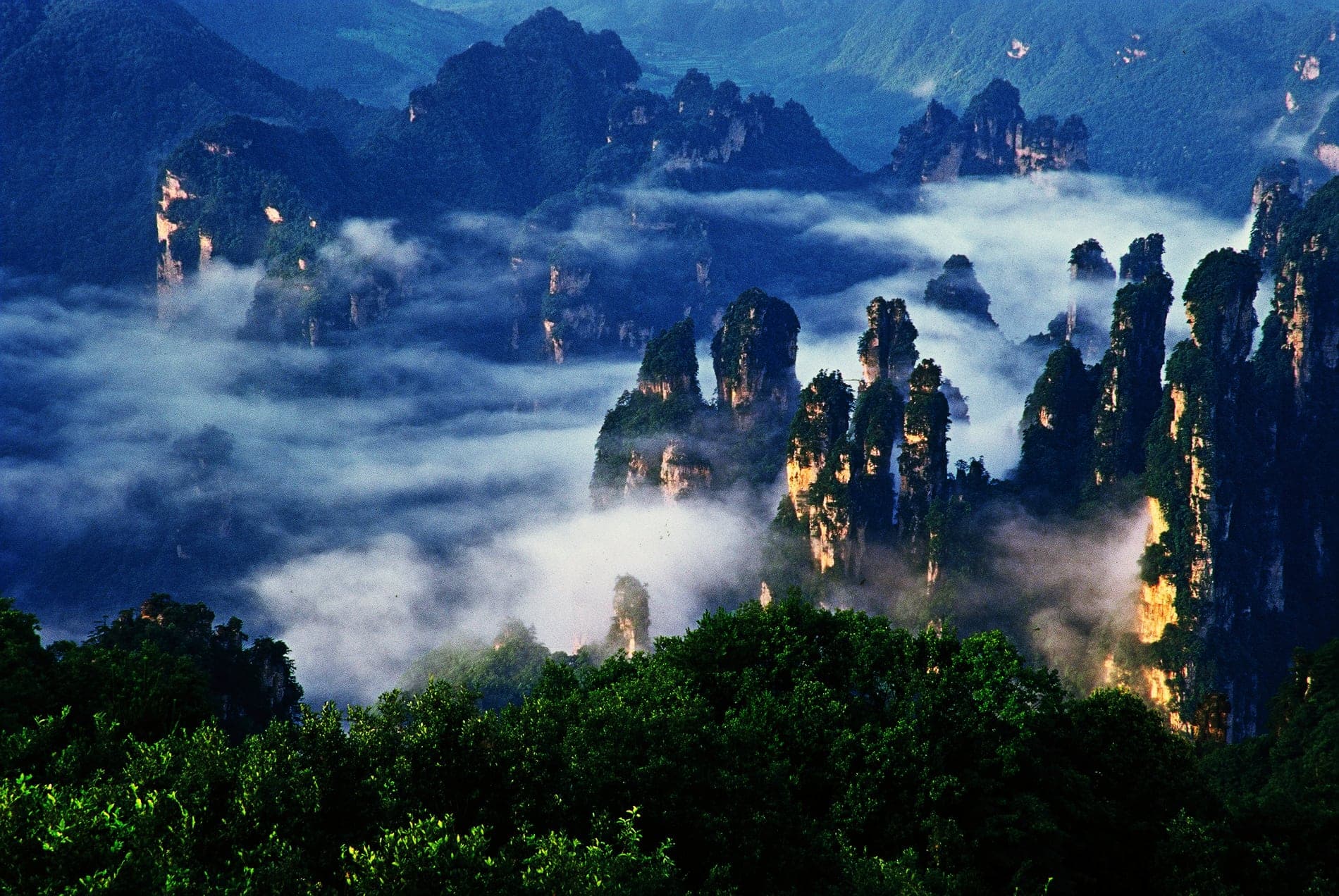 Sandstone peaks rising through blue-toned cloud at dusk.