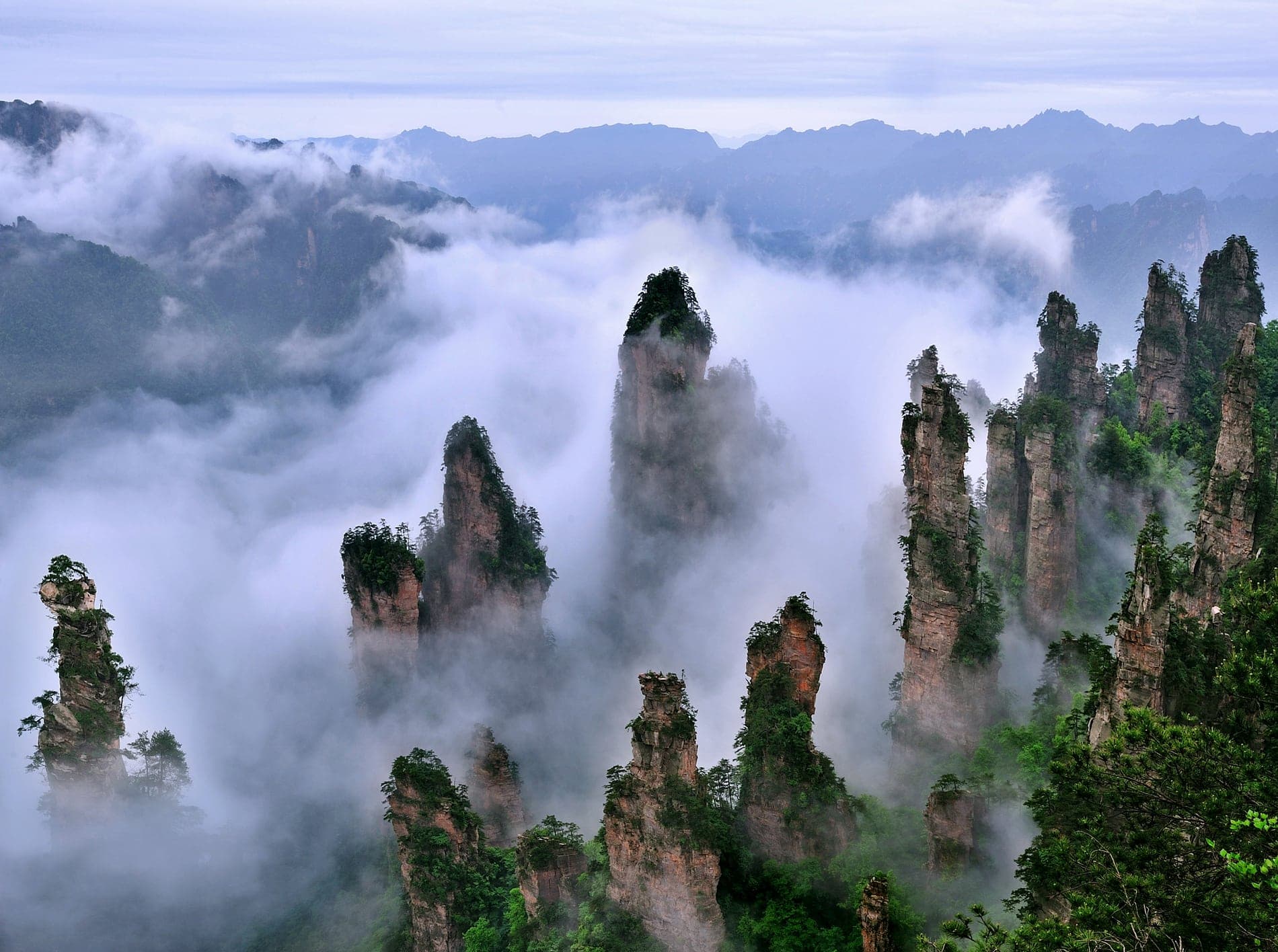 Layers of sandstone pillars emerging from mountain mist.