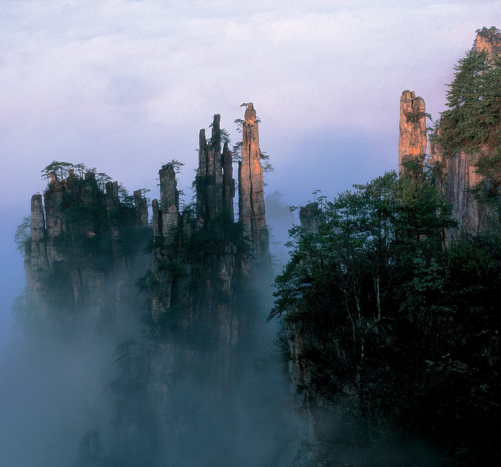 A group of sandstone pillars standing above a layer of cloud.